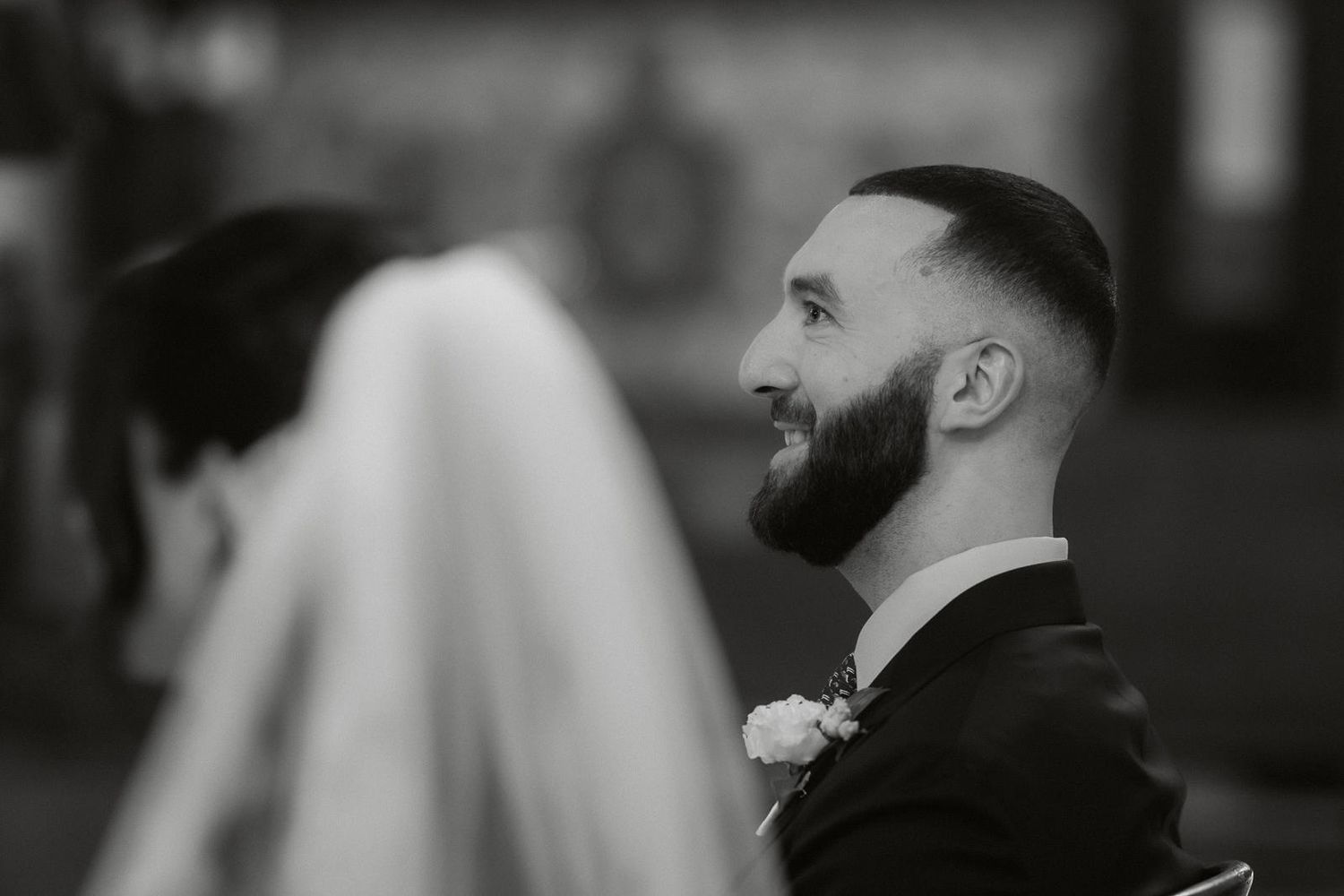 Black and white candid shot of wedding guests during an emotional moment at a ceremony.