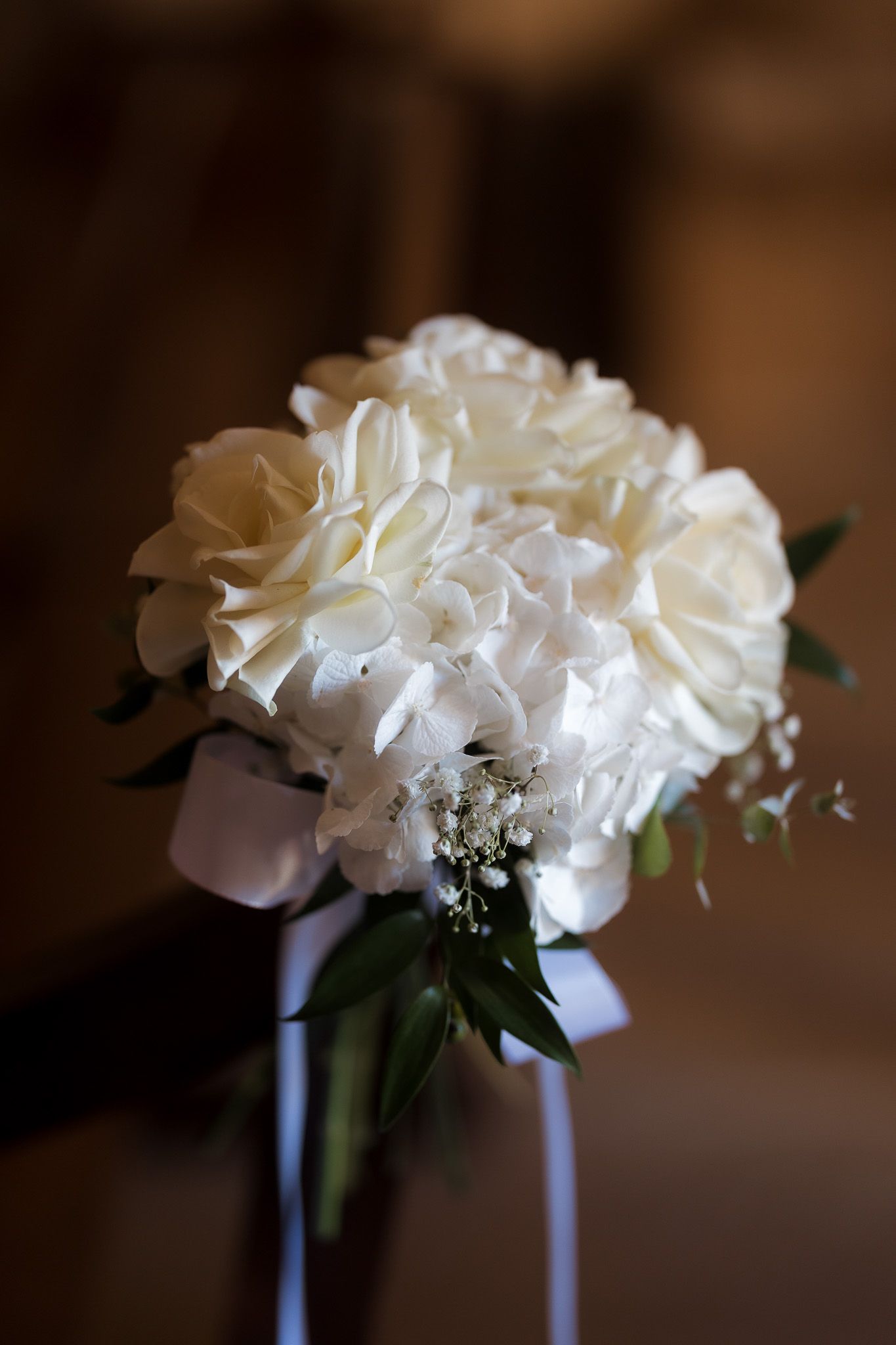 Elegant bridal bouquet of white roses and hydrangeas tied with white ribbon, perfect for weddings.