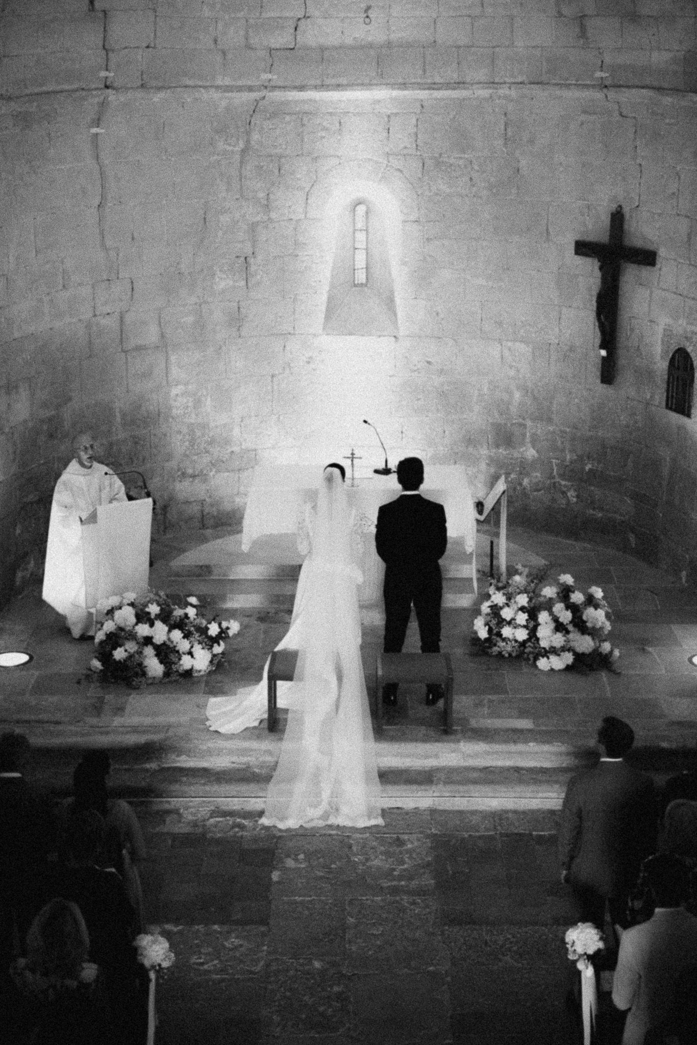 Black and white photo of a bride and groom standing at the altar during a church wedding ceremony.