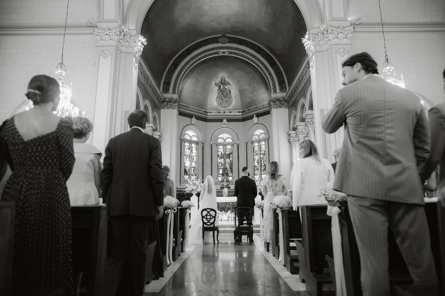 A black and white photo montage shows wedding guests gathering inside an ornate church sanctuary during a ceremony.