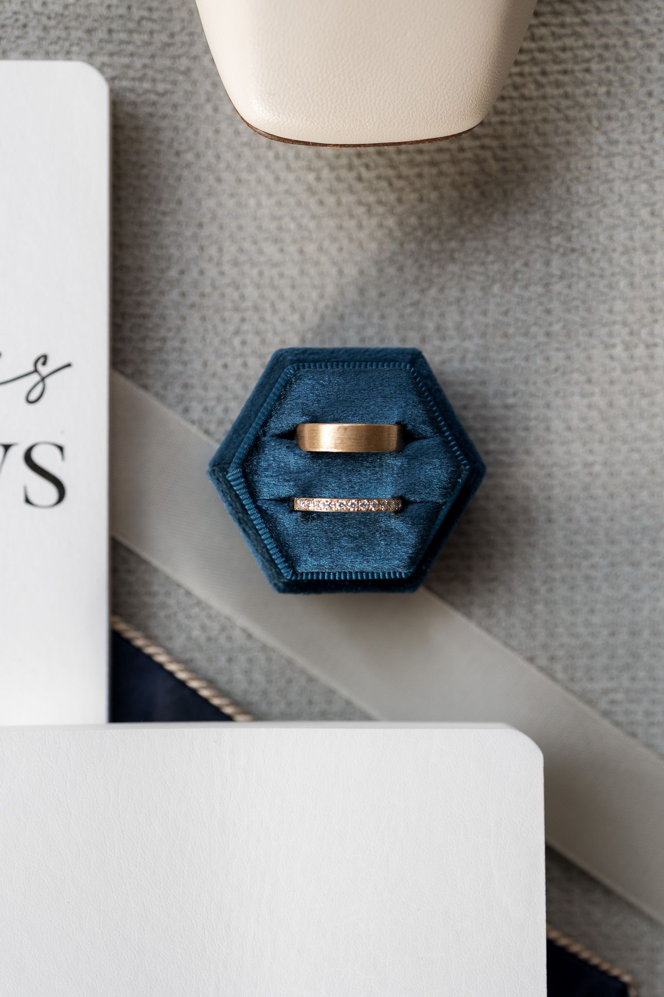 Two wedding bands in a blue velvet hexagon ring box on a white surface.