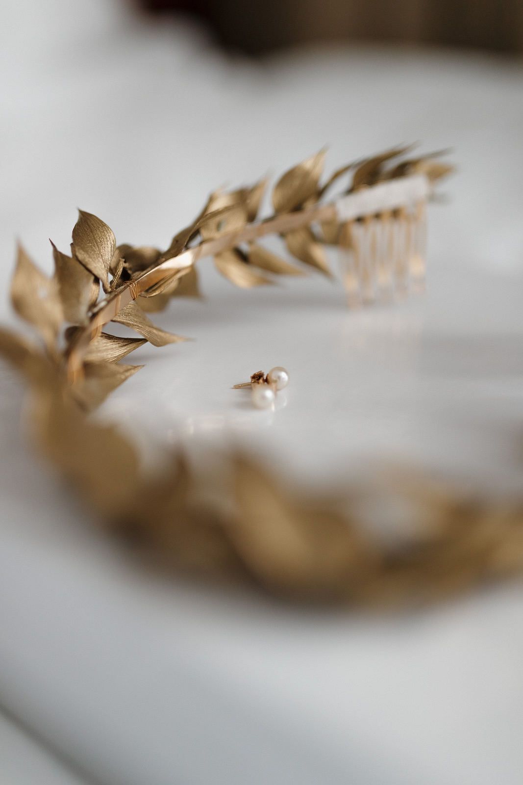 A delicate gold leaf crown or headpiece with intricate details photographed on a light surface.