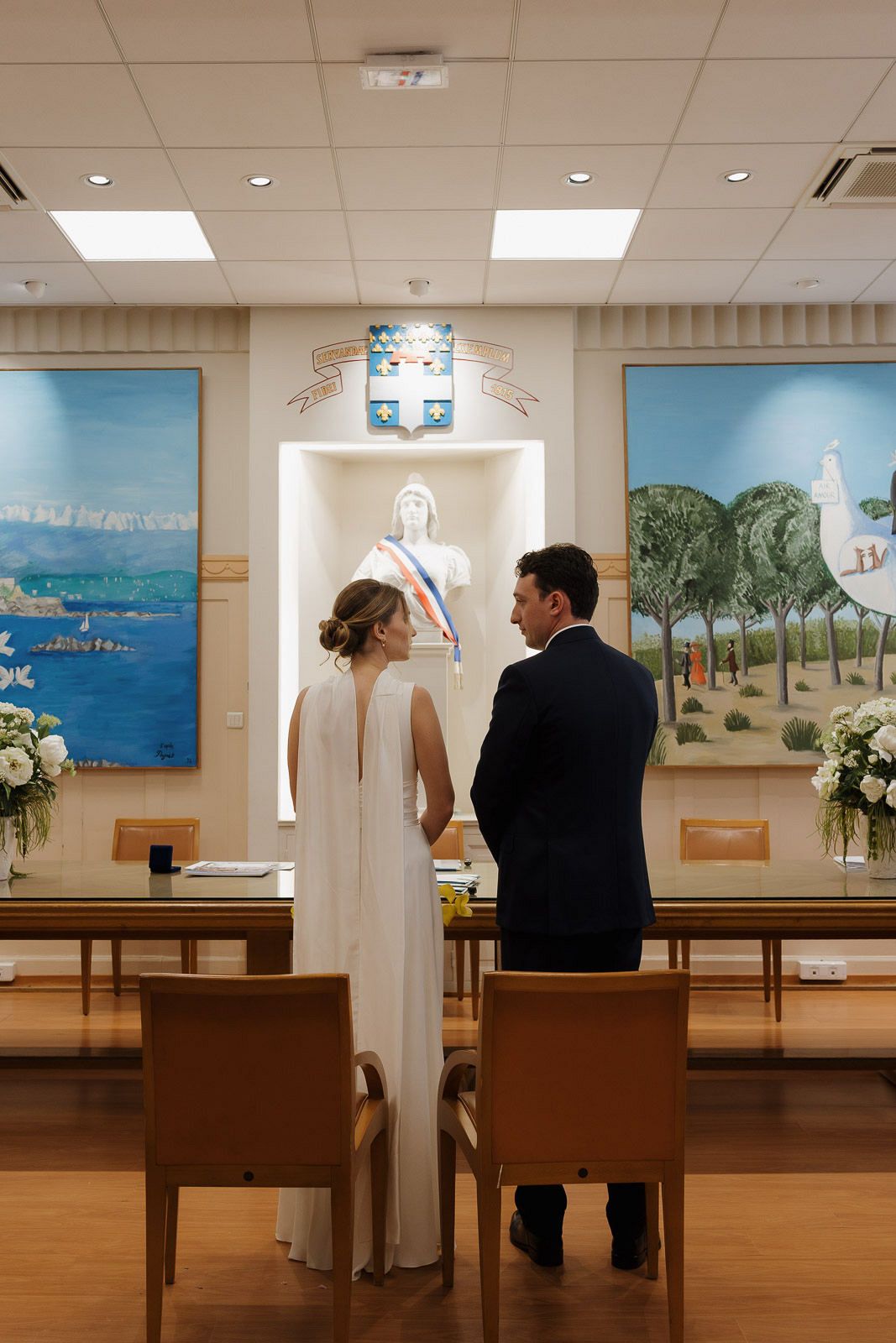 A panoramic sequence showing a couple in wedding attire walking through a church hall decorated with coastal artwork.