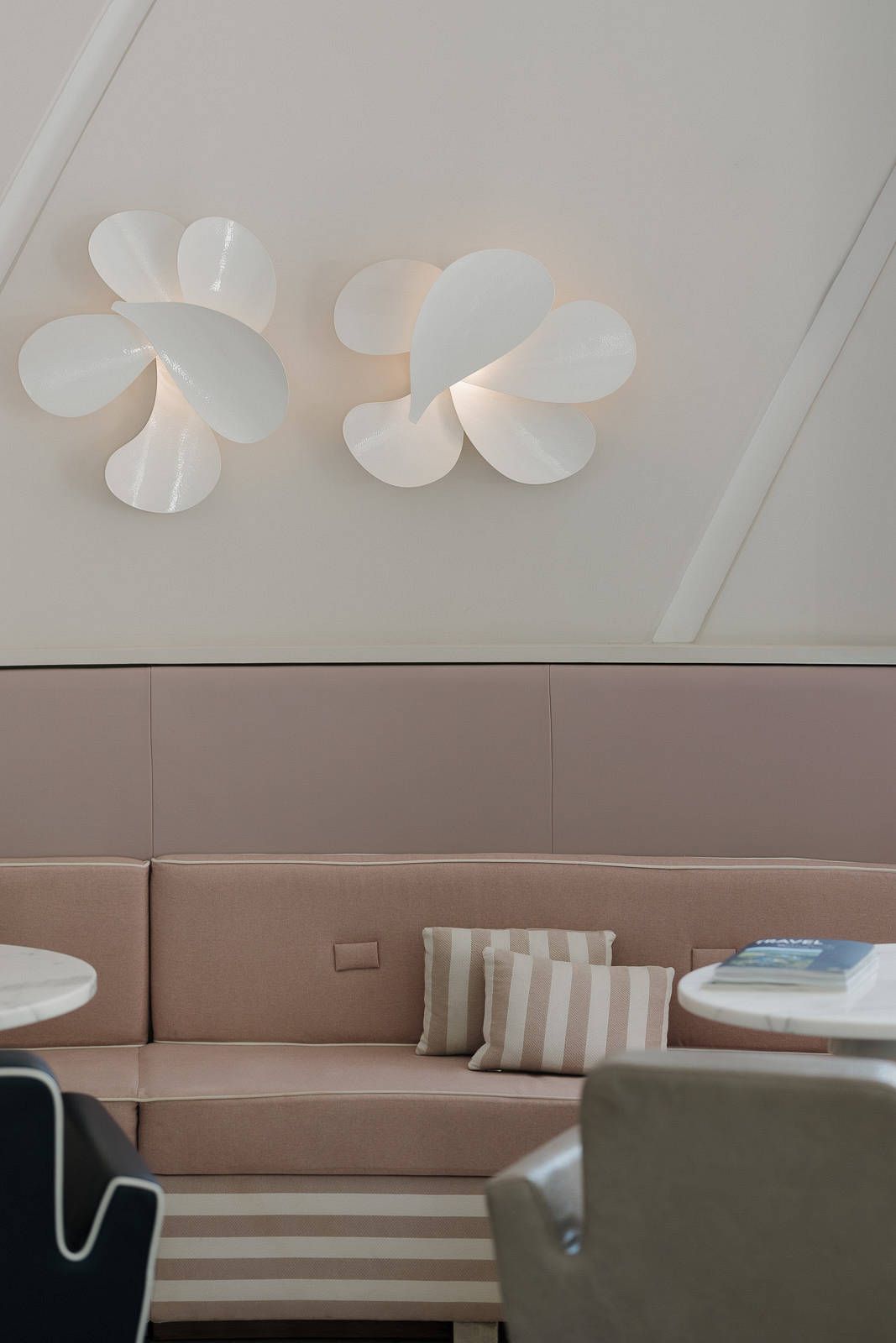 White paper butterfly decorations mounted on a light colored wall above a beige upholstered bench seating area.