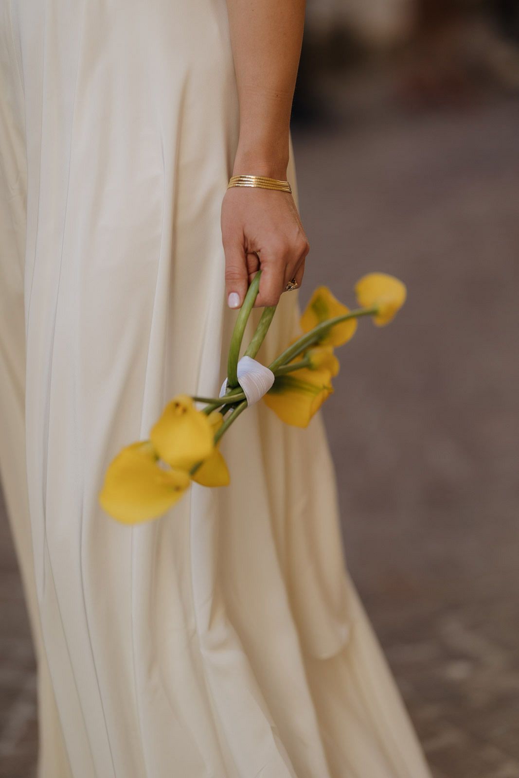 A close-up view of yellow flowers against a flowing white wedding dress fabric.