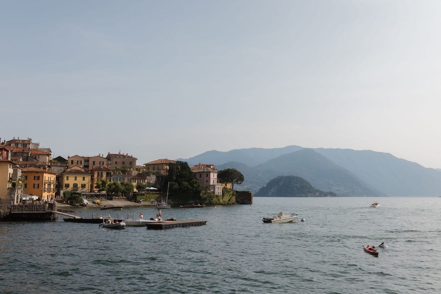 Panoramic view of boats floating in the Mediterranean Sea with coastal buildings and mountains in the background.