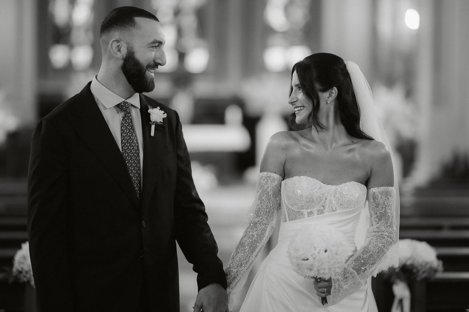 Elegant wedding ceremony scene in a church with soft lighting and decorative floral arrangements.