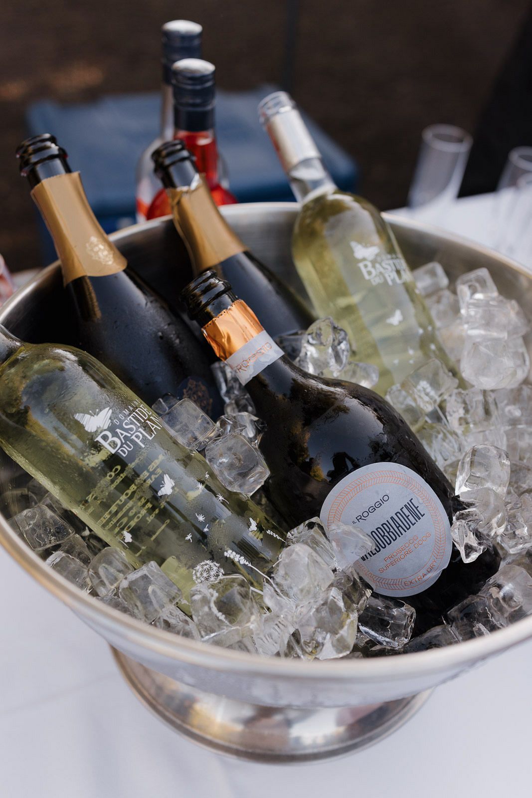 Wine and champagne bottles chilling in a silver ice bucket with crushed ice at an elegant event.