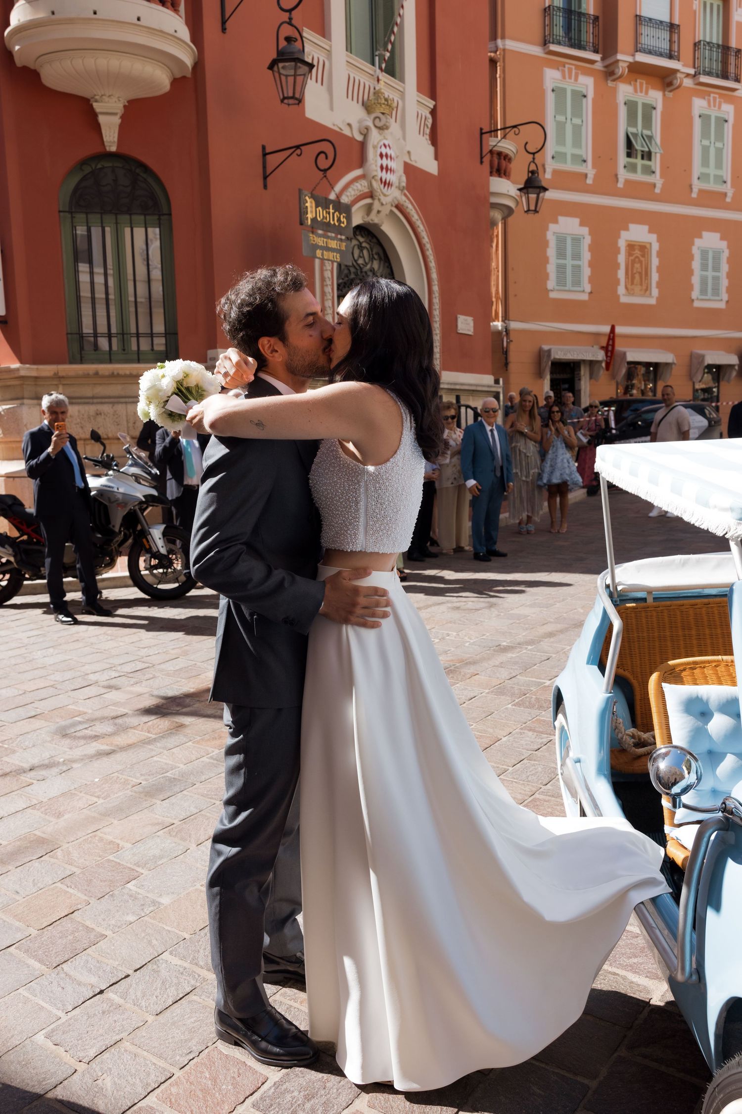 Bride and groom share a kiss outside a colorful European building on their wedding day.