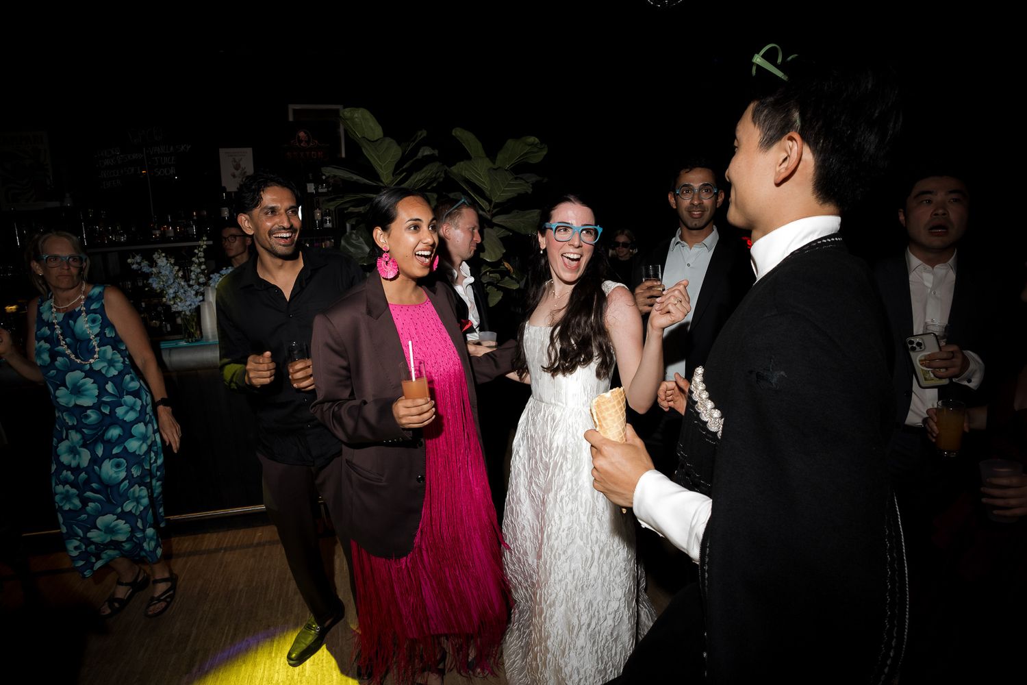 Guests dancing and celebrating at a lively wedding reception party in elegant formal attire.