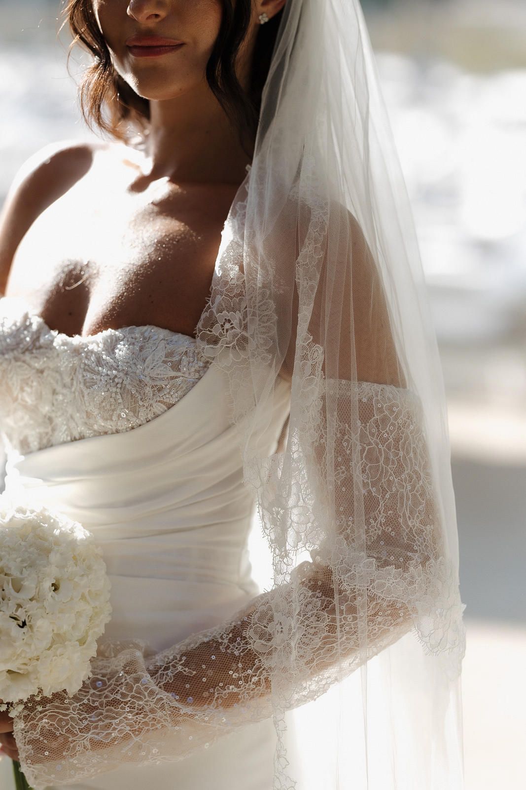 Close up details of delicate white lace and tulle on an elegant wedding dress with veil.