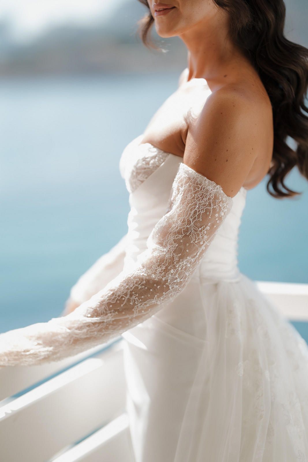Close-up view of a delicate lace sleeve on an elegant white wedding gown with intricate floral detailing.