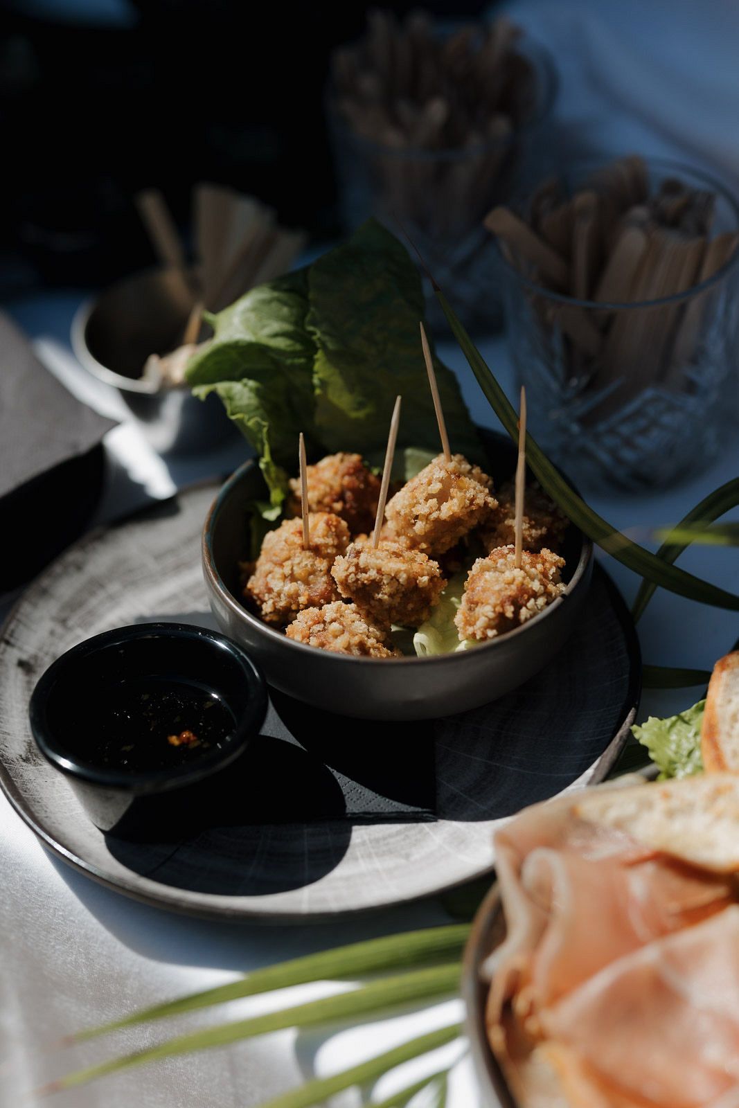Appetizer plates with fried bites and dipping sauces arranged on a dark surface.