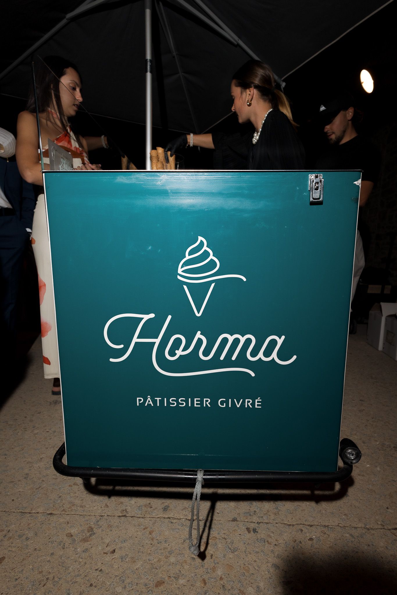 Horma Patissier Givre teal ice cream cart sign displayed at an outdoor evening event.