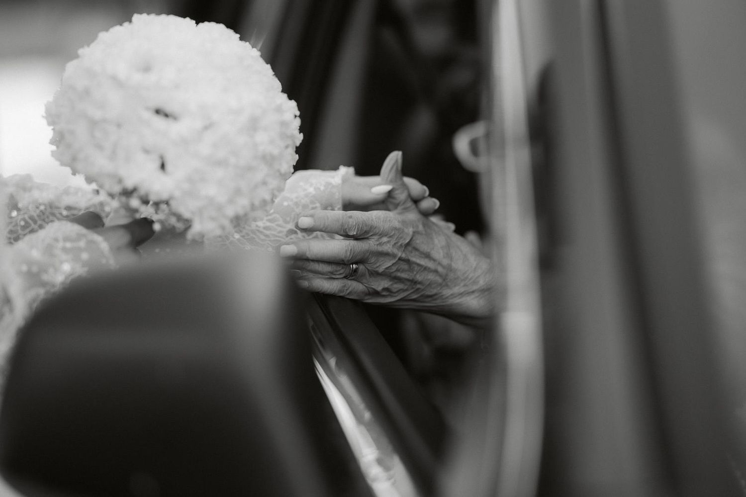 A black and white photograph shows someone holding a small piece of cake or dessert on a plate.