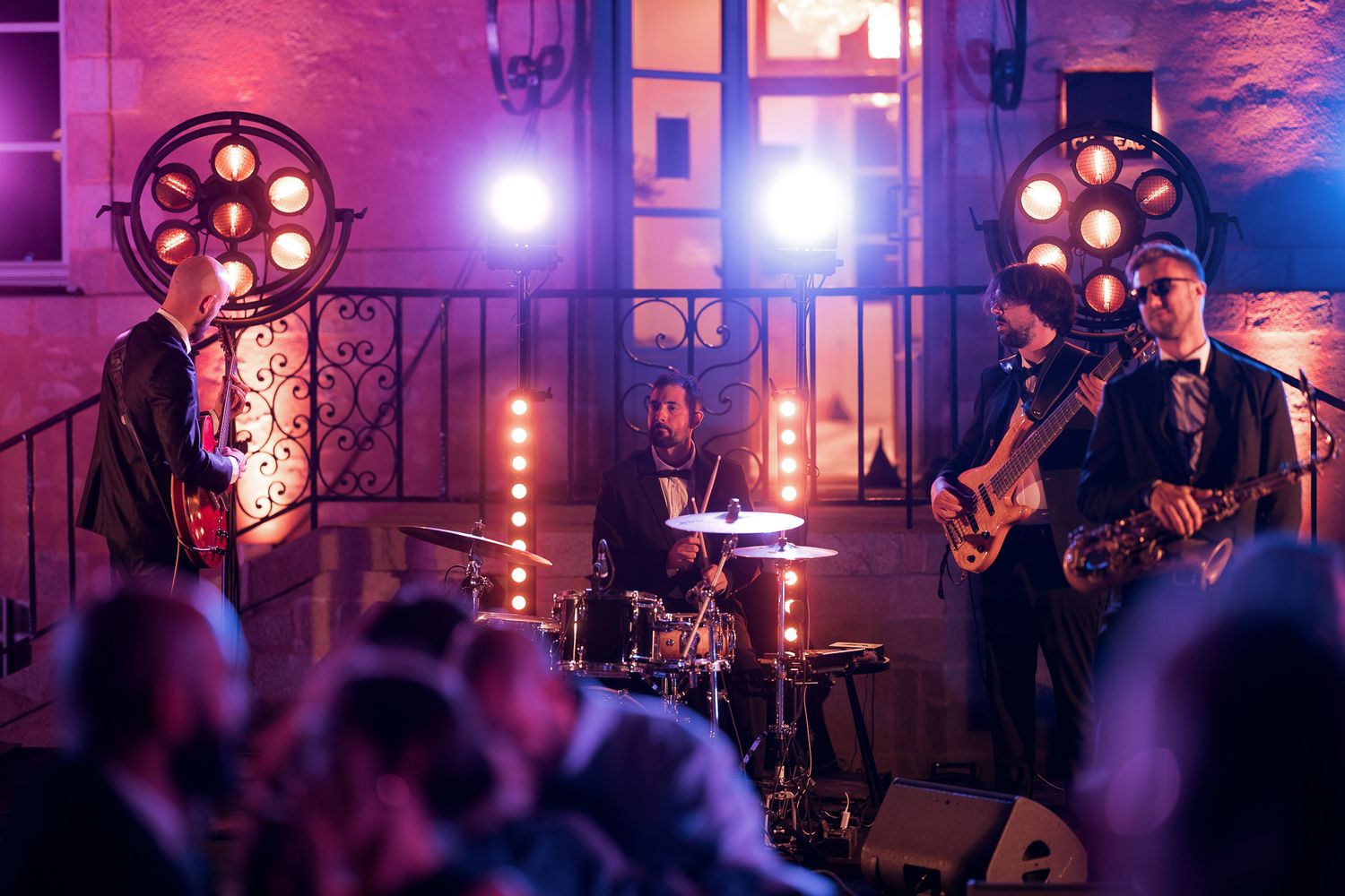 Live band performing on stage with dramatic lighting at an elegant evening venue event.