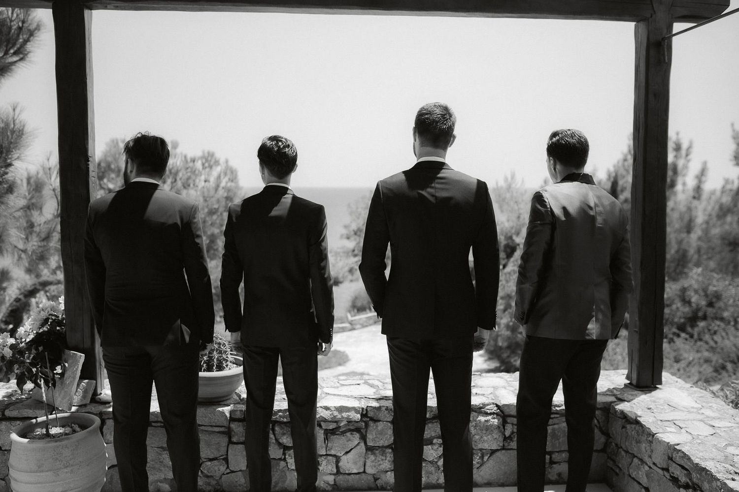 A black and white panoramic image shows silhouettes of people standing in a line against a bright background.