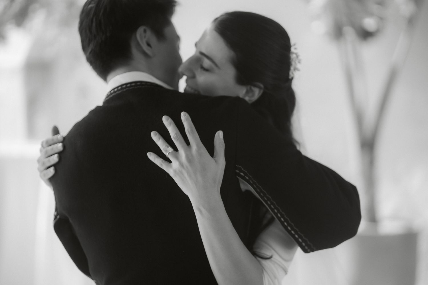 Black and white photo of a couple embracing and kissing tenderly at a romantic event.