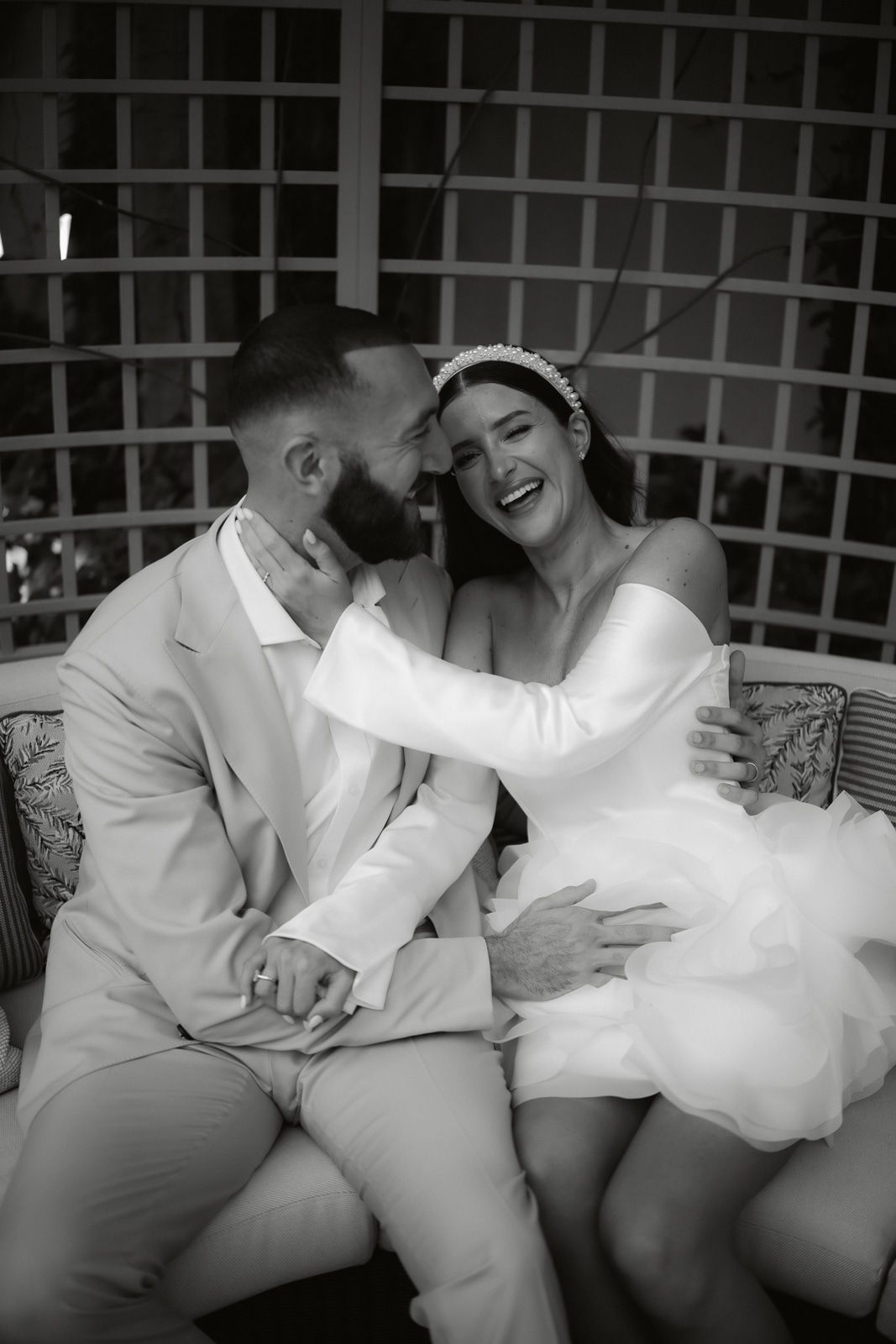 A sequence of black and white photos showing a couple in white clothing sitting close together on a couch.