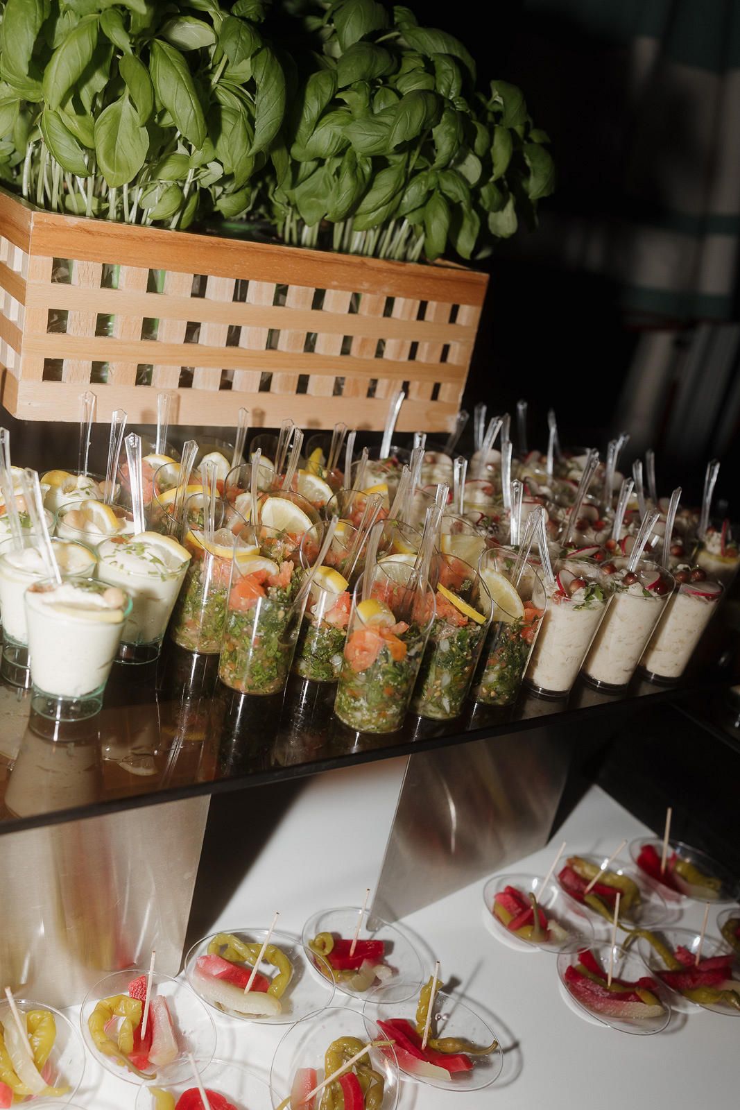 Long table display of elegant appetizers and cocktails arranged in glass vessels for an upscale catering event.