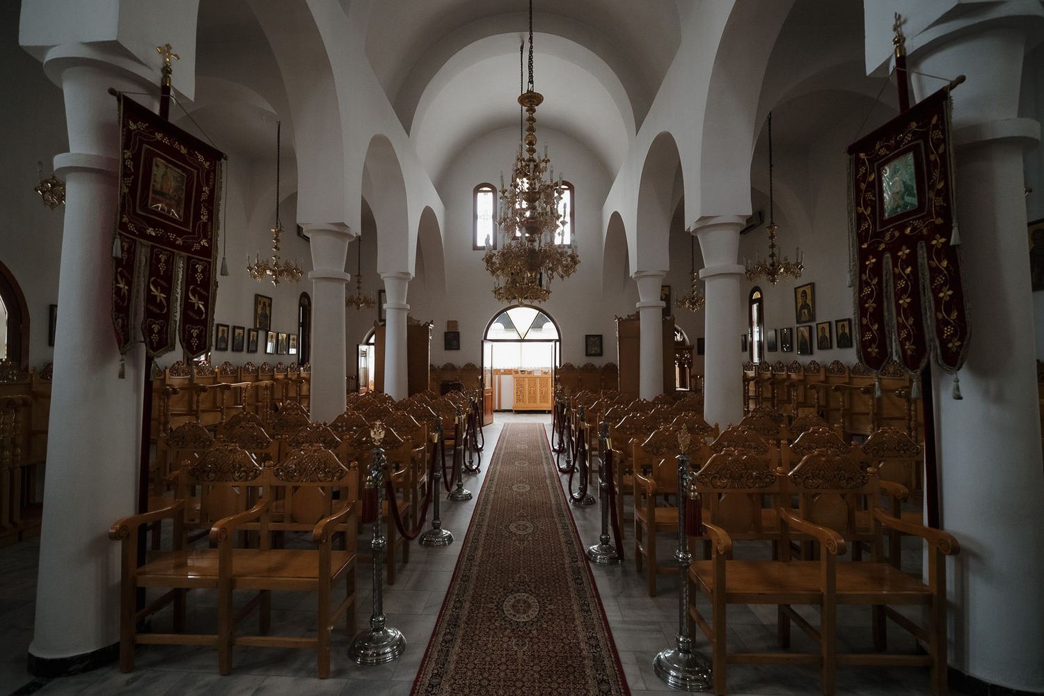 Interior view of a historic church sanctuary with wooden pews and white columns leading to an illuminated altar.