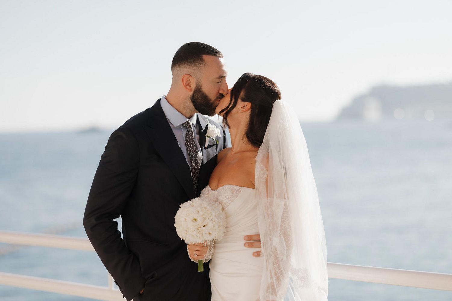 A couple shares an intimate moment on their wedding day against a mountain backdrop.