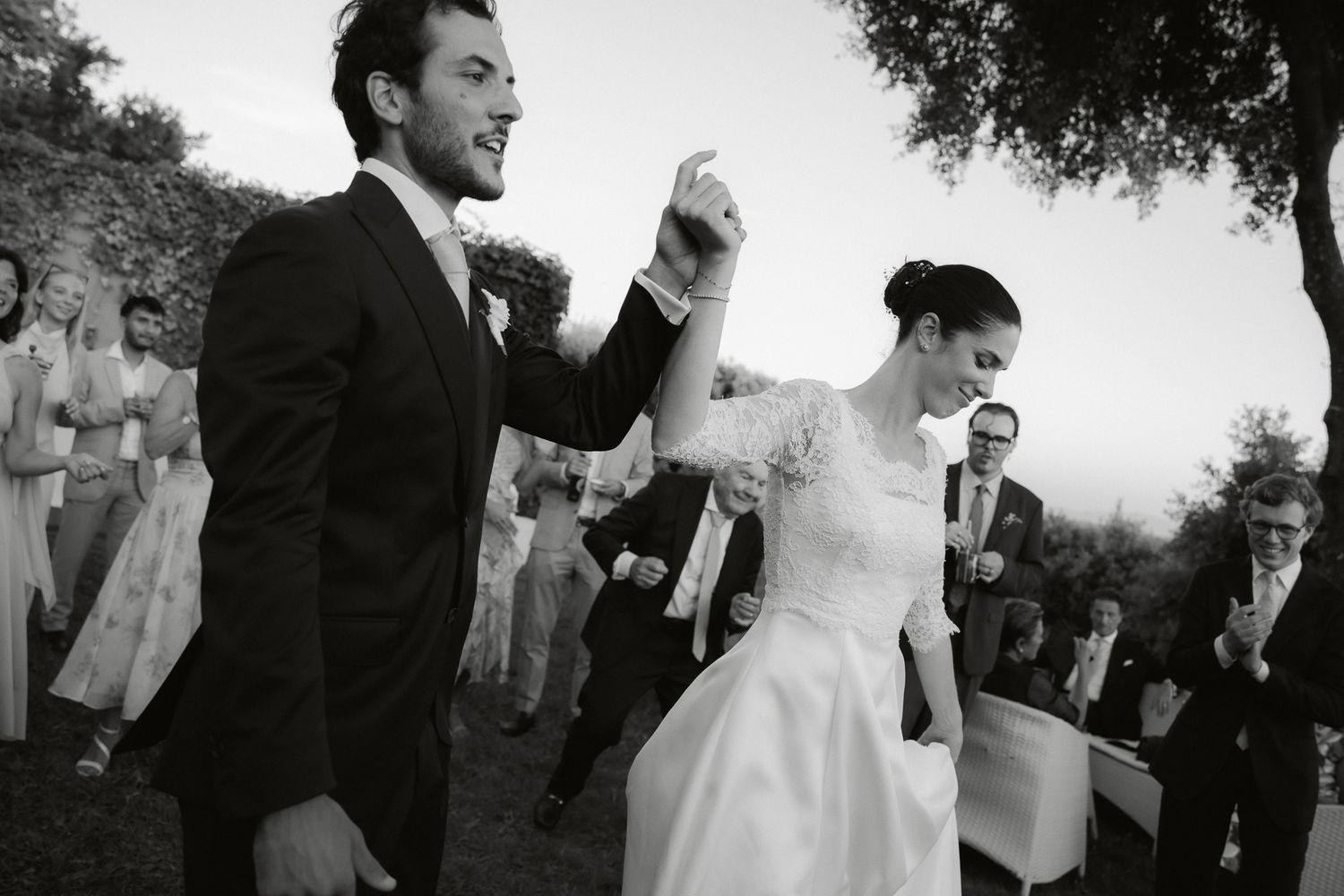 Black and white photo of a joyful bride and groom walking down the aisle after their outdoor wedding ceremony.