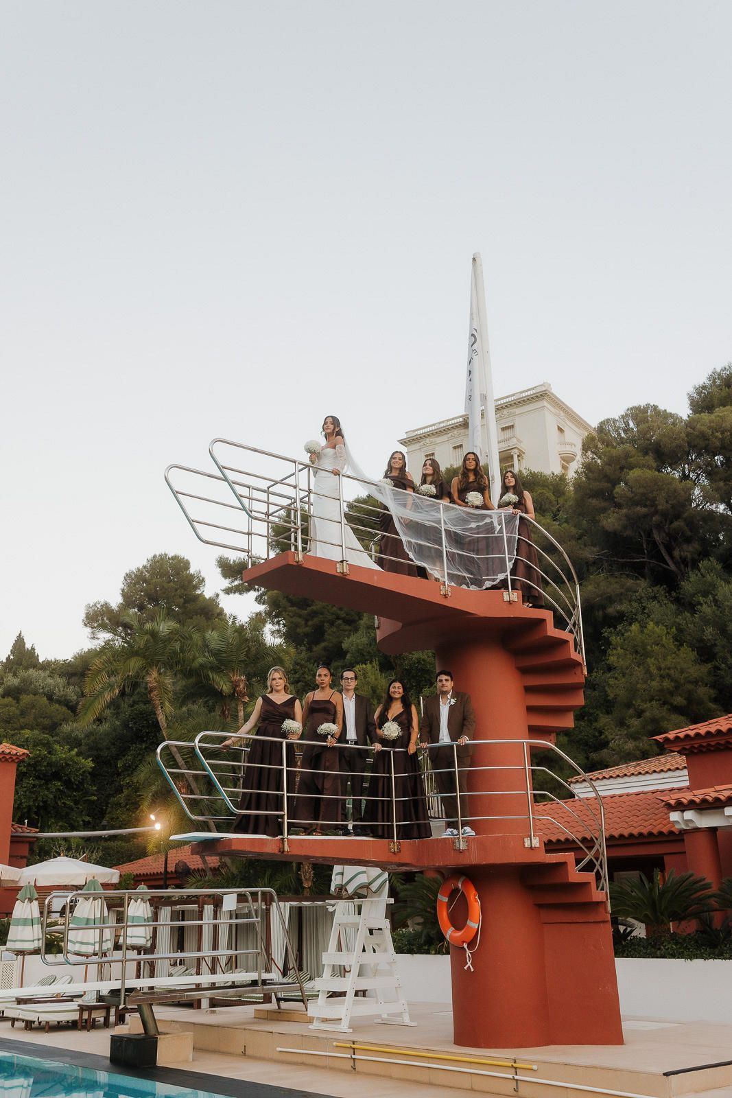 Vintage diving boards and platforms at a retro swimming pool with red metal structures against a sunny sky.