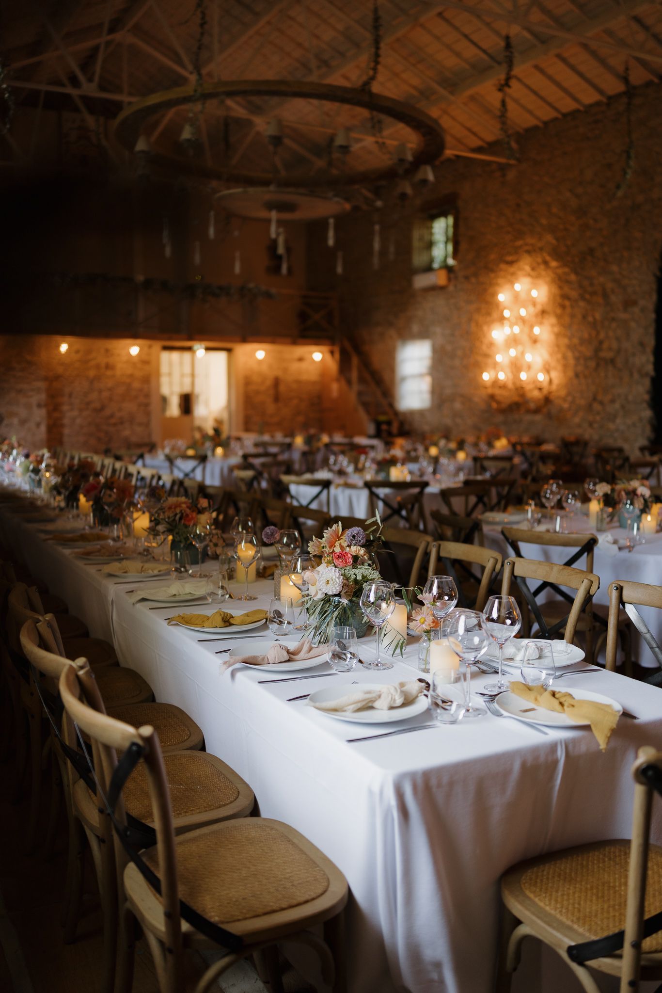 Rustic barn wedding reception with elegant table settings and warm ambient lighting.