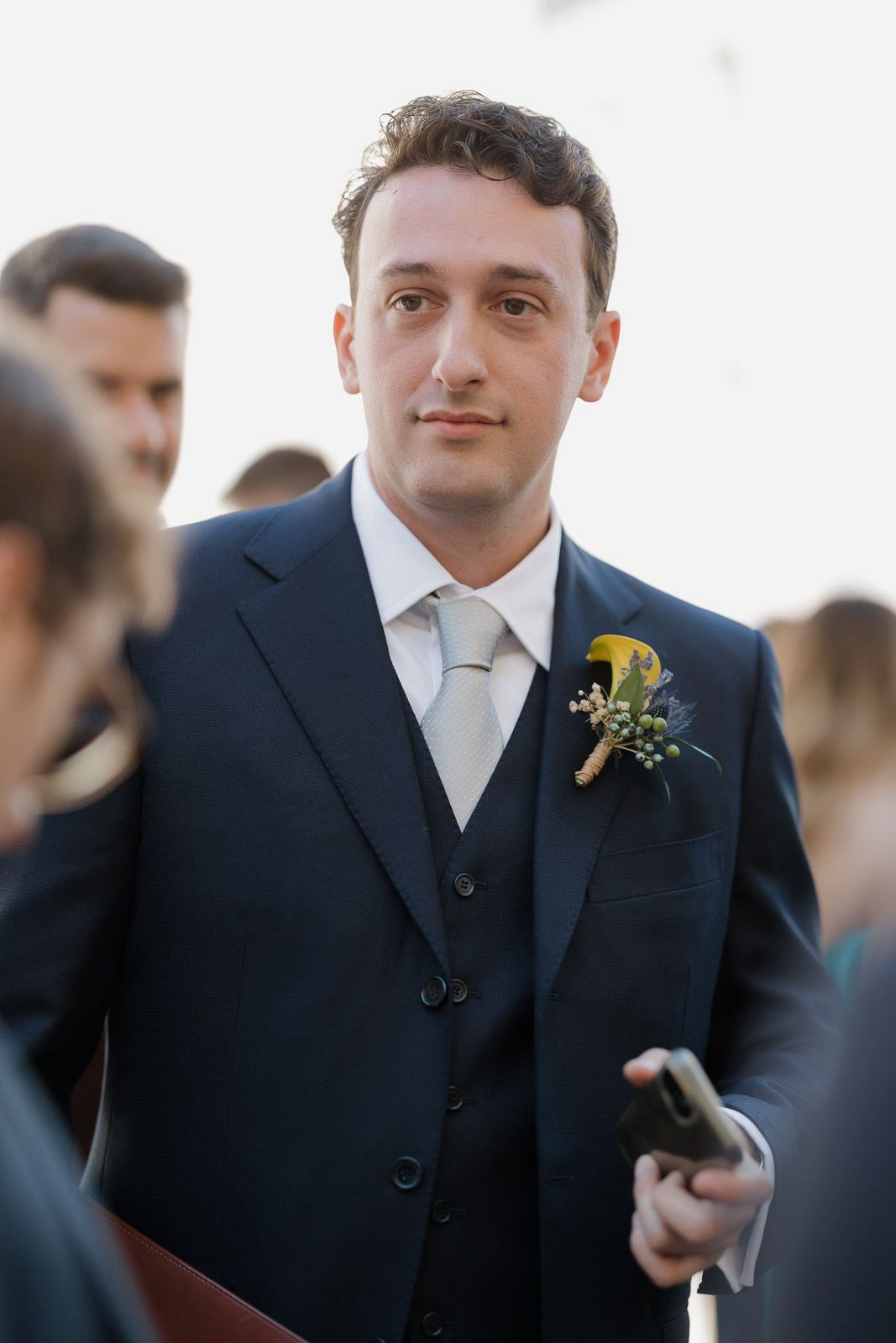 A series of candid shots showing a groom in a dark suit with a yellow boutonniere during a wedding ceremony.