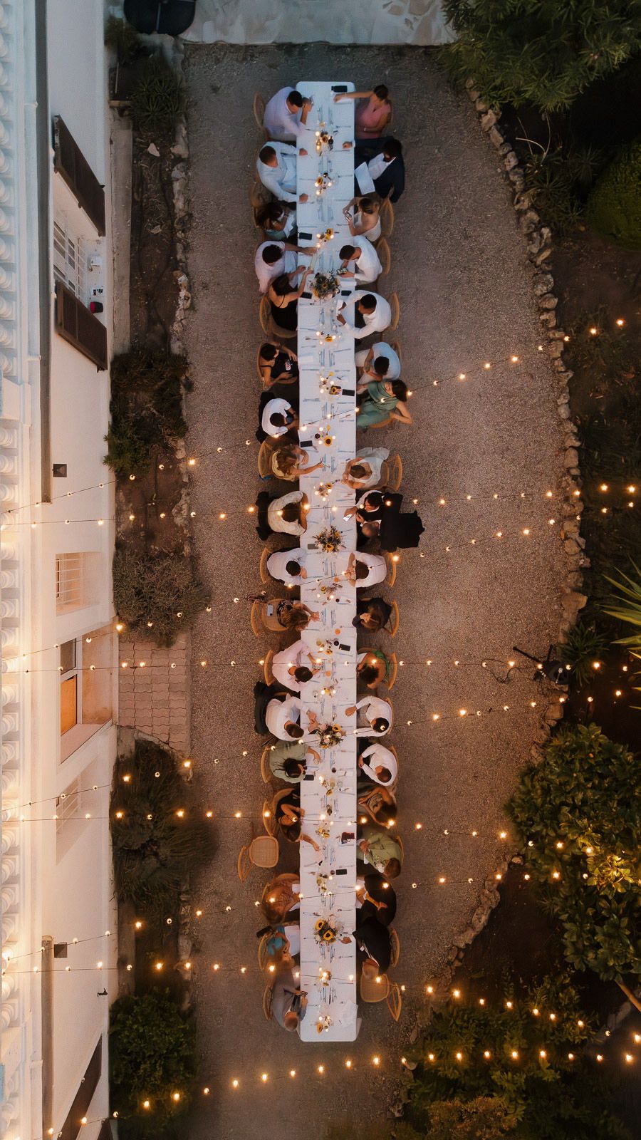 Aerial view of outdoor dining tables with string lights creating an elegant ambiance at night.