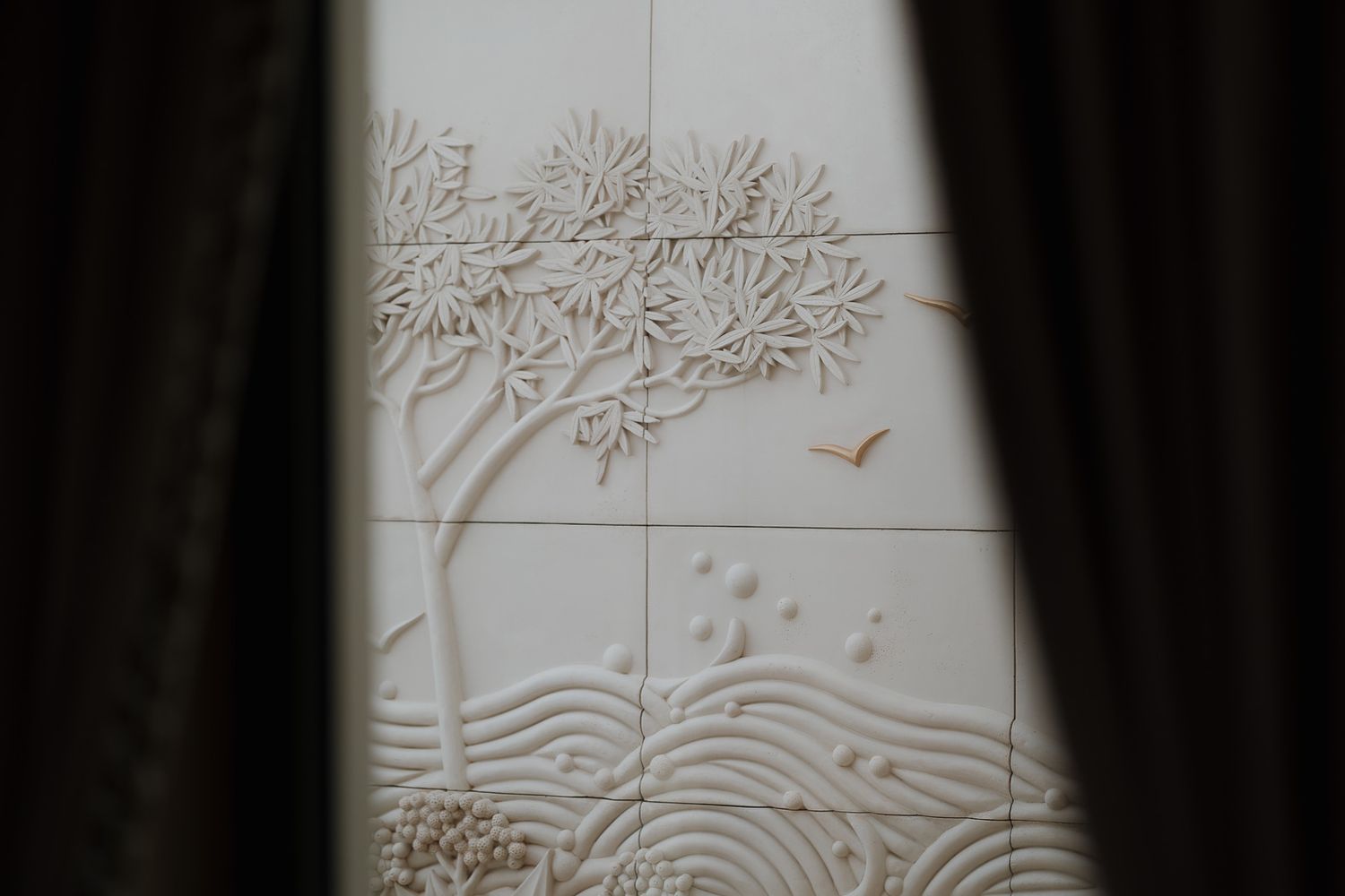 Artistic wall panel with delicate tree and nature motifs etched in a minimalist white design.