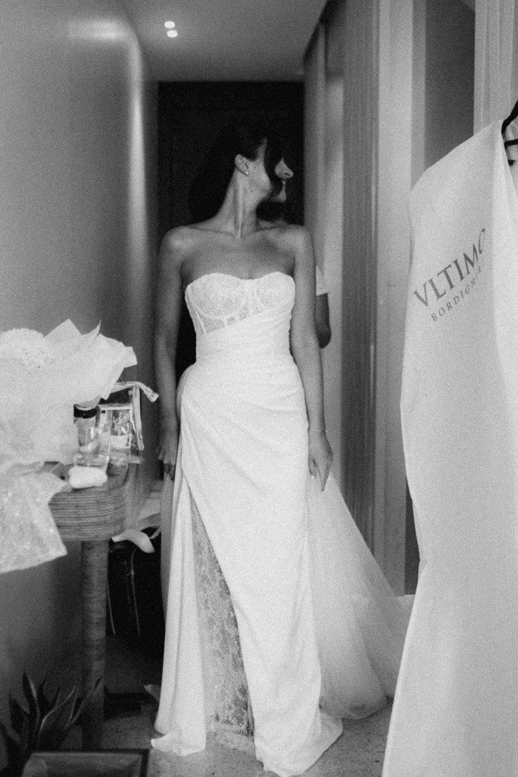 Several white wedding dresses on hangers displayed in a hallway with soft lighting.