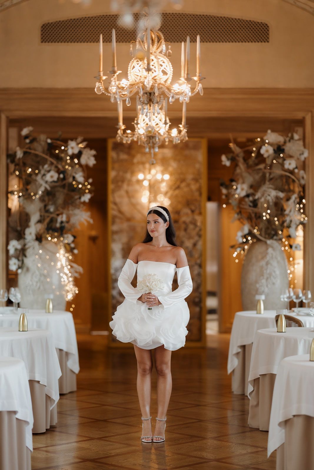 A series of wedding dress photos in an elegant ballroom with chandeliers and white table settings.
