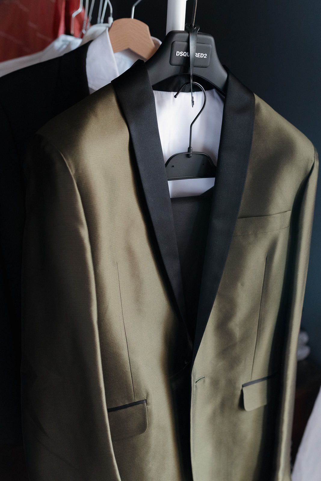 Close-up view of a tailored olive green suit jacket on a black mannequin displaying fine craftsmanship and details.