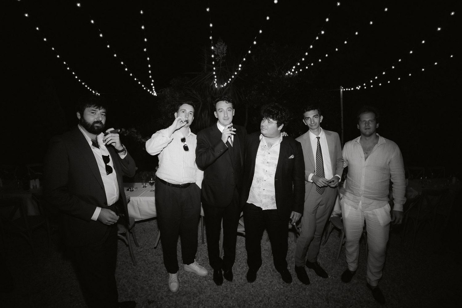 Vintage black and white photograph showing people dancing together in a line formation at a social gathering.