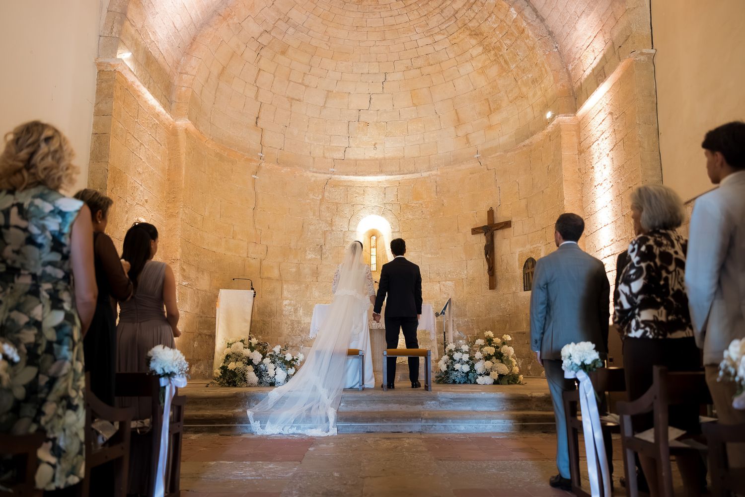 Bride and groom stand at the altar of a rustic stone chapel during an intimate wedding ceremony.