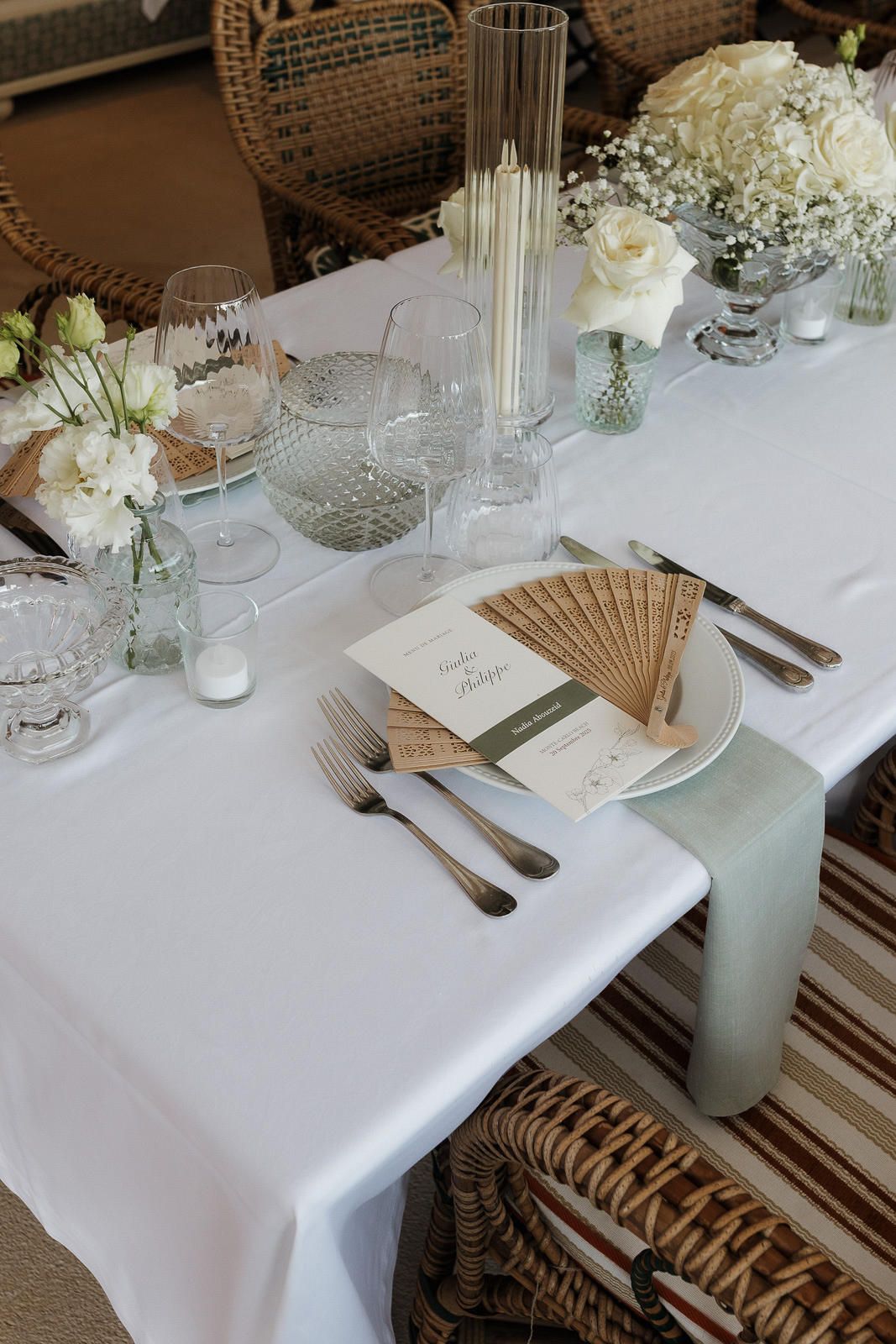 An elegant wedding table setting with white linens, crystal glasses, and delicate floral centerpieces.