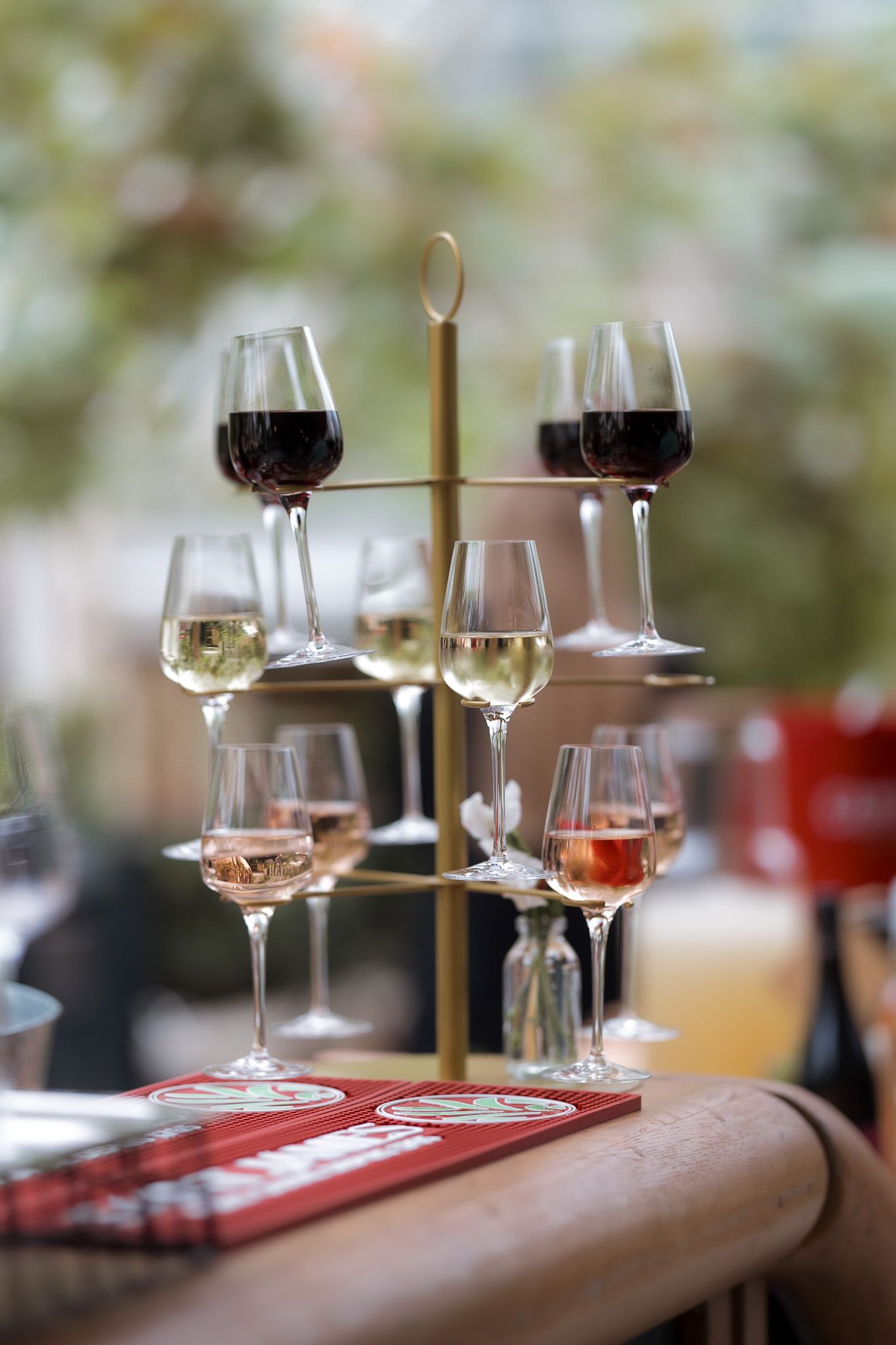 Elegant wine tasting display with red, white, and rosé wines on a gold rack stand at a restaurant.