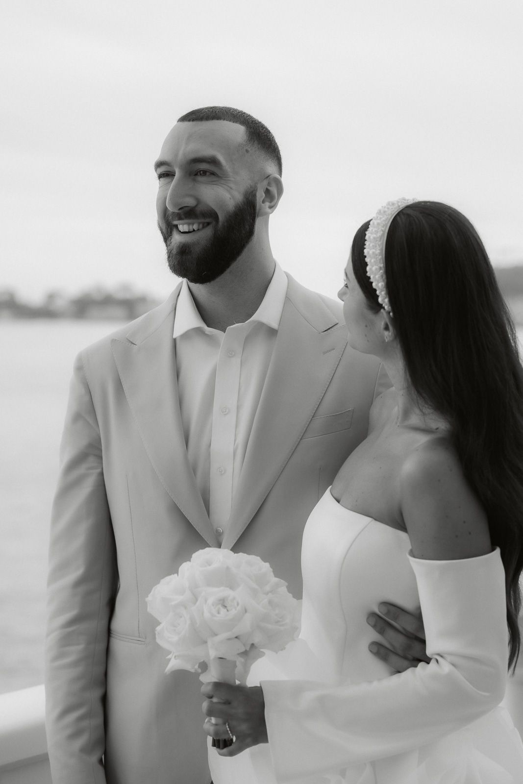 Black and white series of a couple in wedding attire sharing intimate moments on a beach.