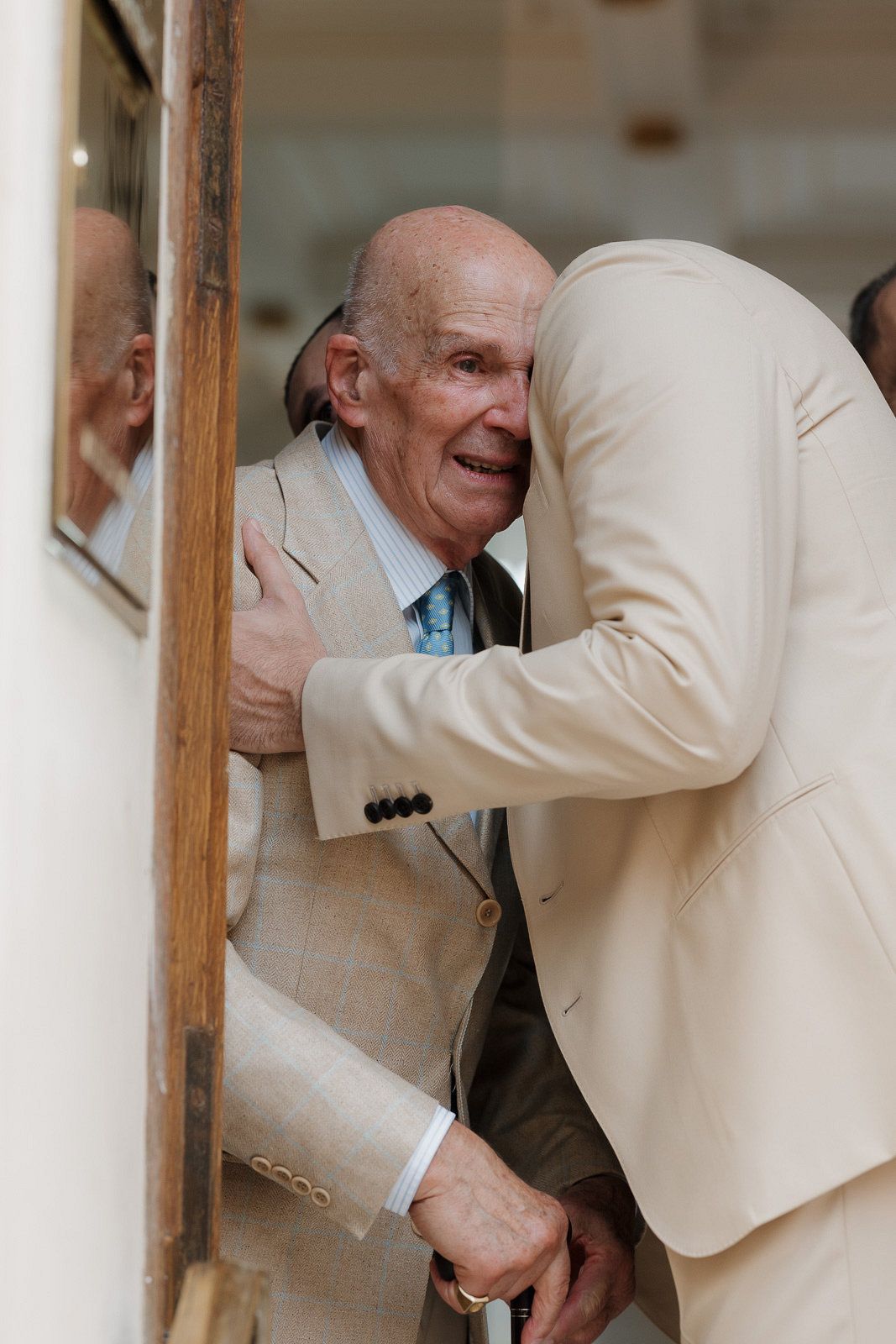 A sequence of four photos showing a person in a cream-colored suit jacket peering through a wooden structure.