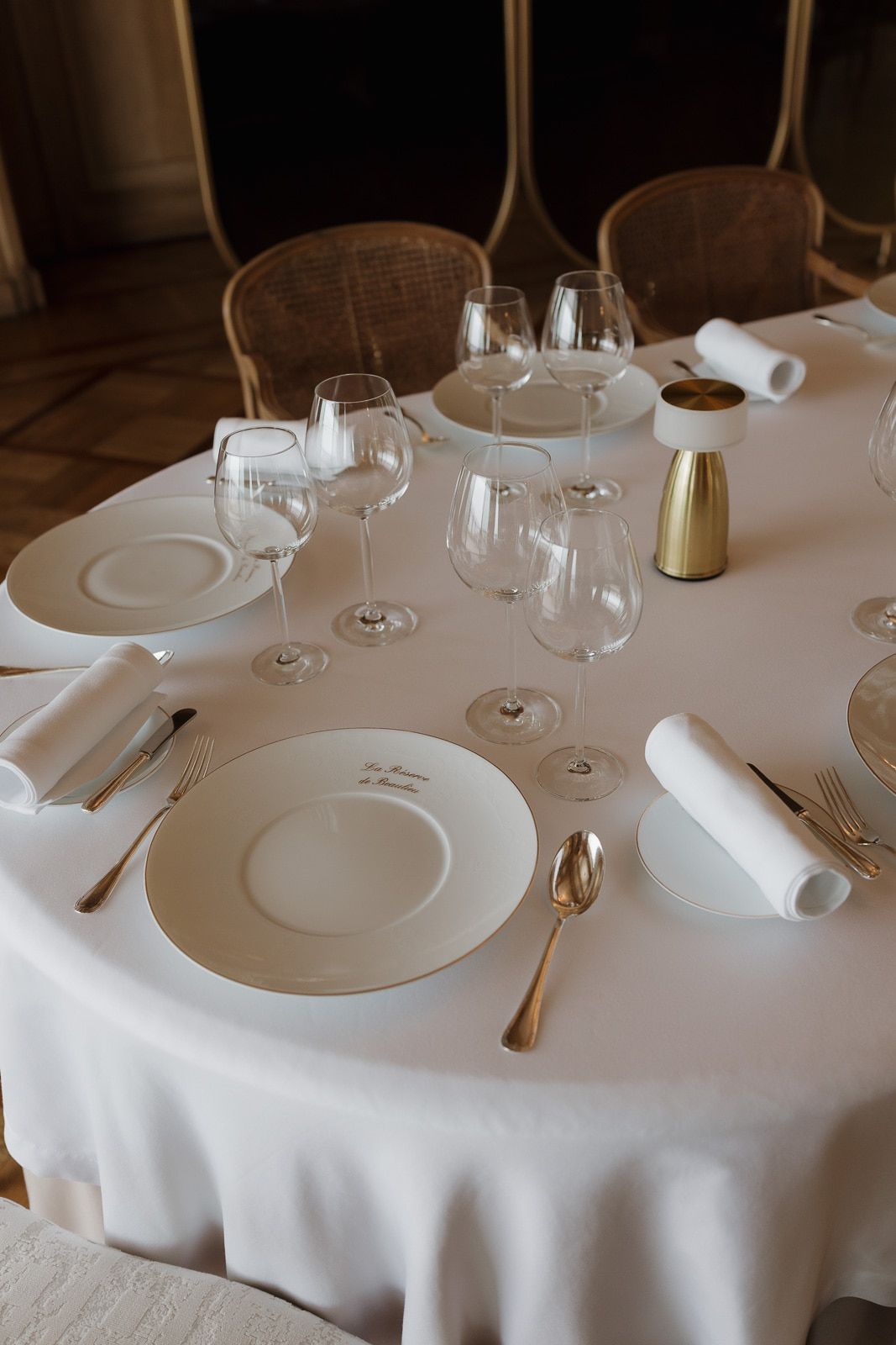 Elegant table settings with white linens, wine glasses, and plates arranged in a fine dining restaurant.