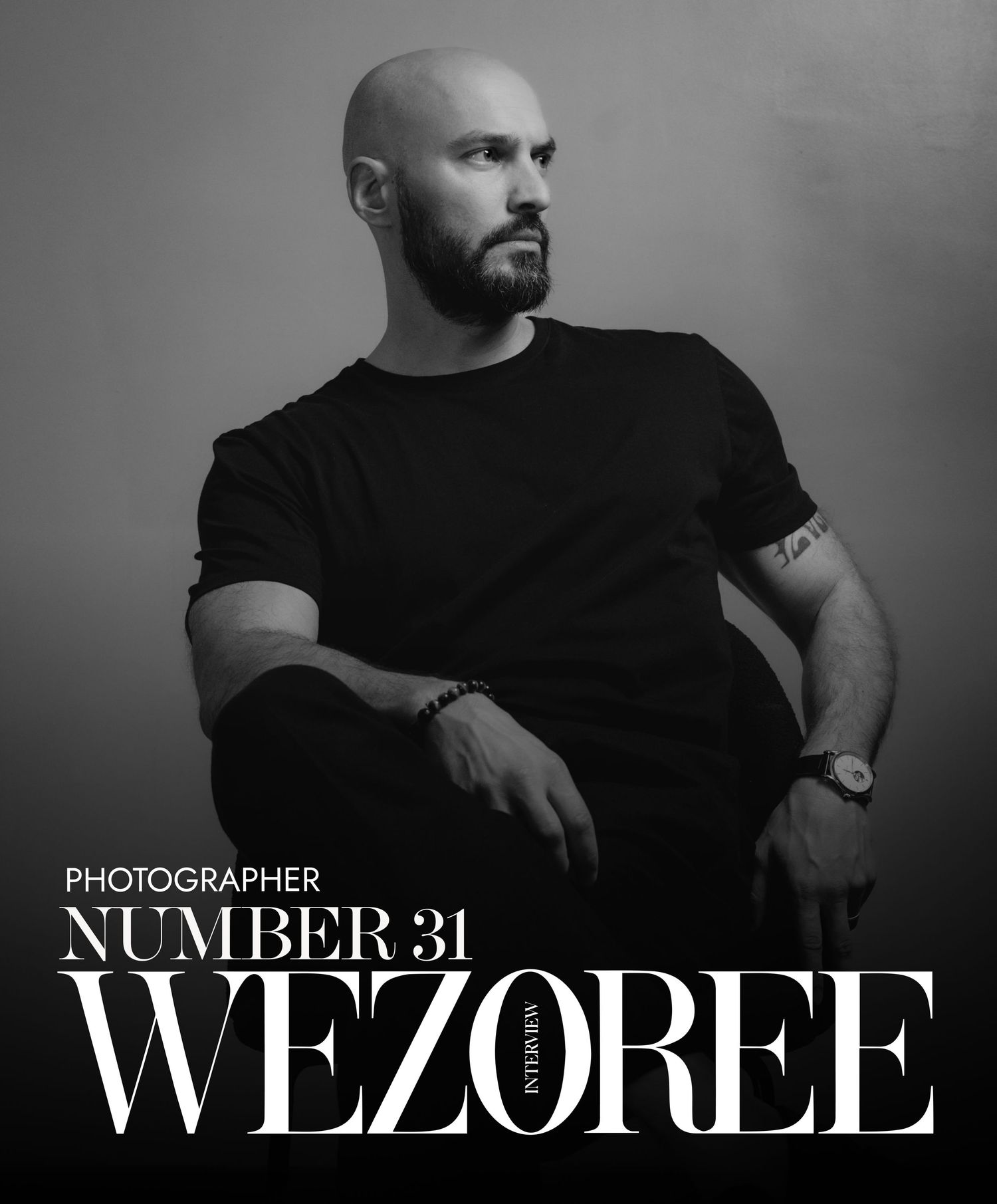 Black and white portrait of a bald, bearded photographer in a dark t-shirt seated and looking aside, on a Wezoree Number 31 magazine cover.