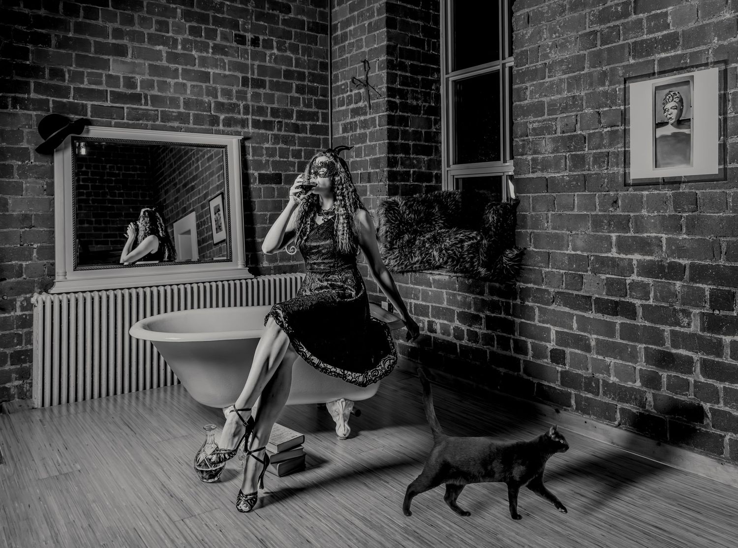 Black and white photo of interior scene with piano bench, mirror and small black cat.