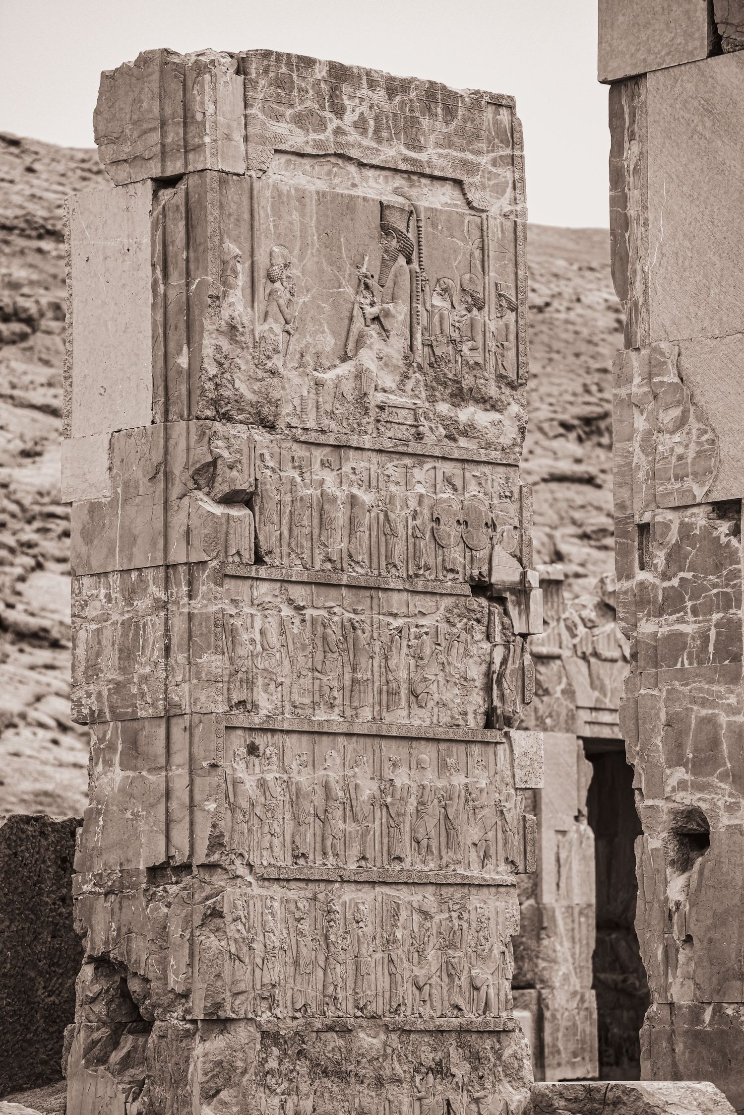 Stone relief carvings depicting ancient Persian scenes and figures arranged in horizontal registers.