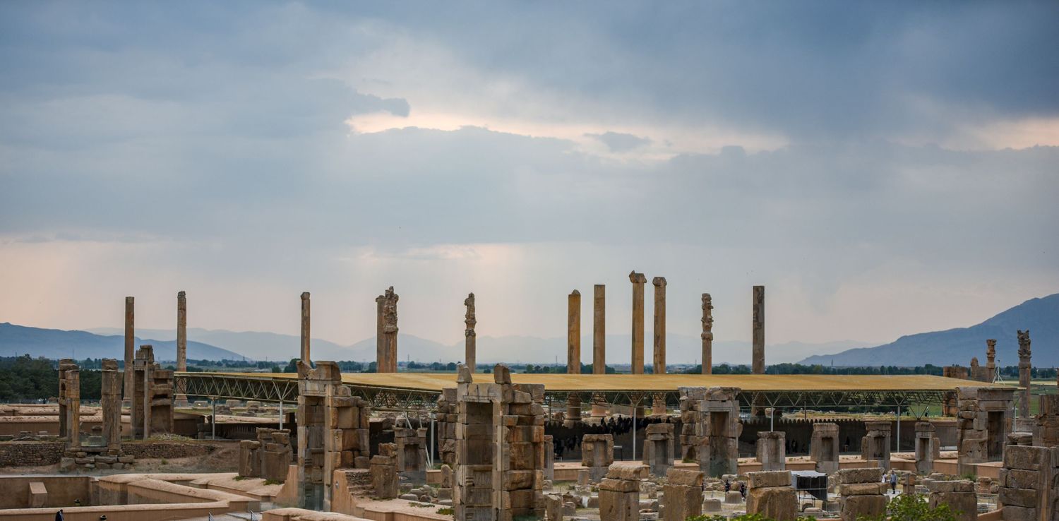 Ancient stone columns and ruins standing under dramatic cloudy sky.