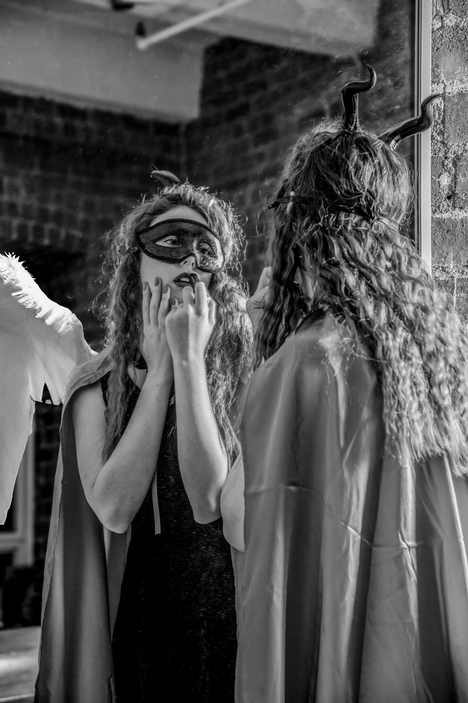 Dramatic black and white photo of masked figures with long hair in theatrical poses.