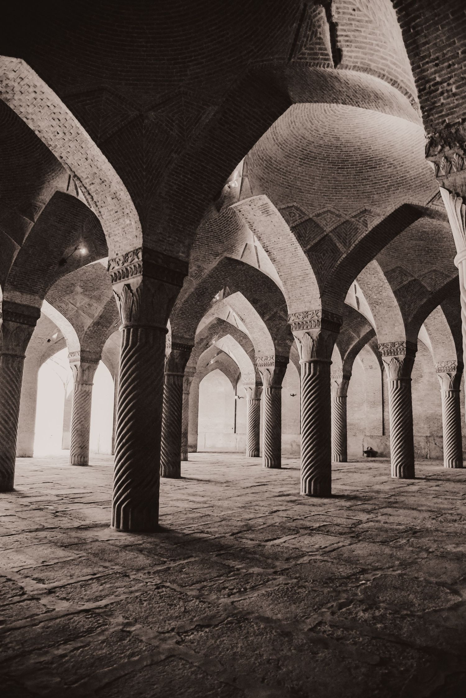 Historical mosque interior featuring twisted columns and repeated arches in dramatic black and white.