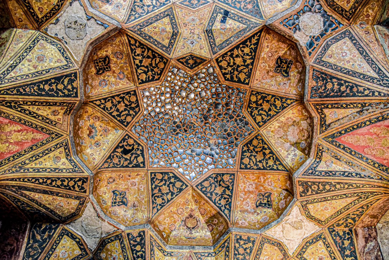 Detailed view of an ornate Islamic dome interior featuring geometric patterns and floral designs in rich colors.