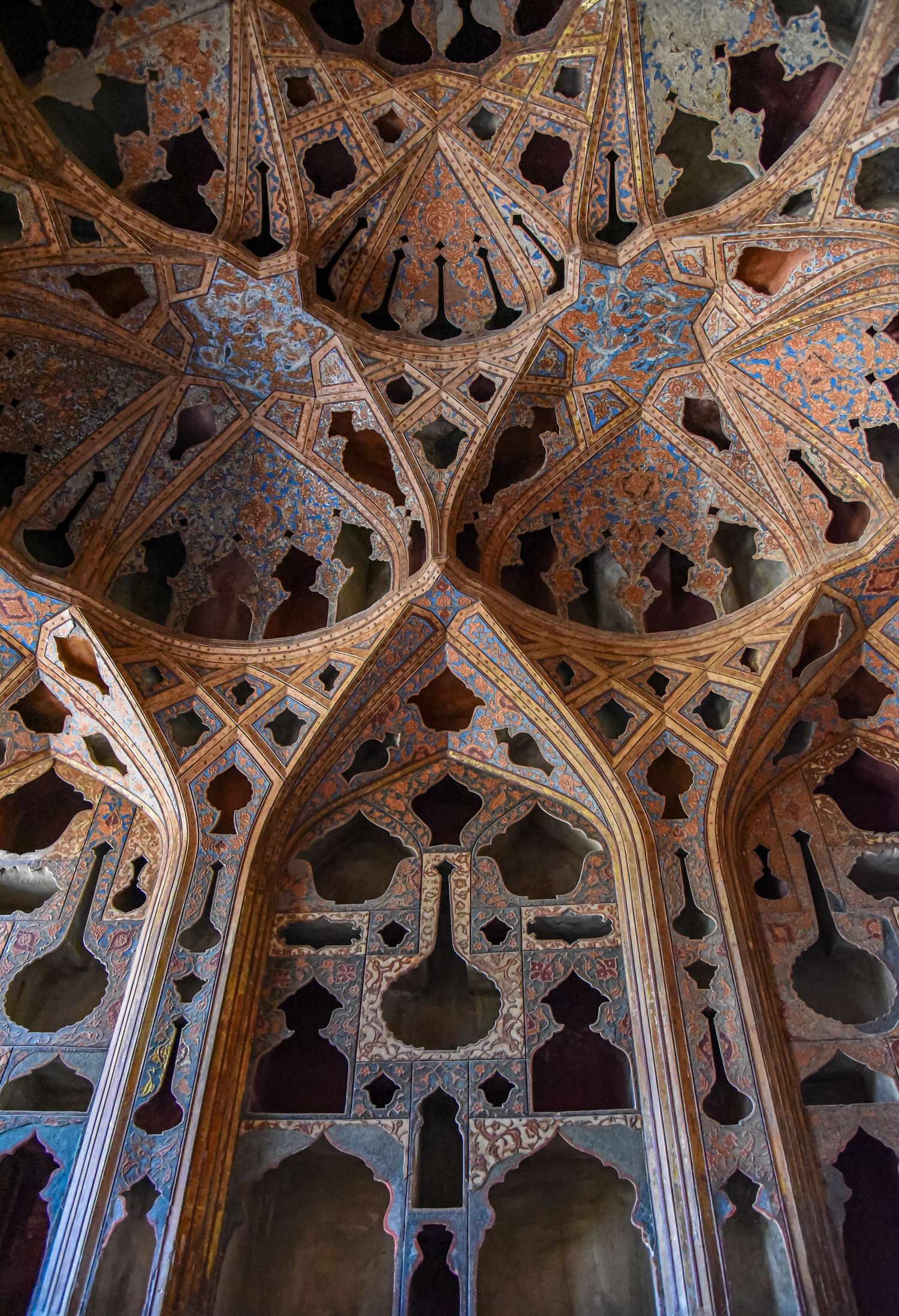 Detailed view of intricate muqarnas vaulting with geometric Islamic patterns in warm tones.